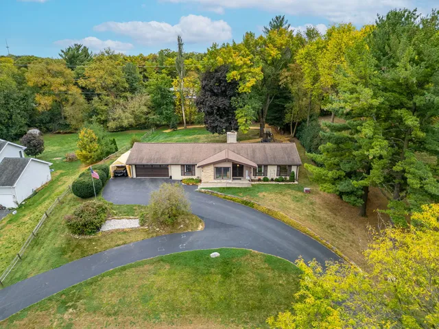 an aerial view of a house with swimming pool lawn chairs and large trees