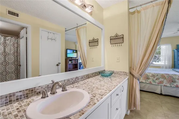 a en suite bathroom with a granite countertop sink and a mirror