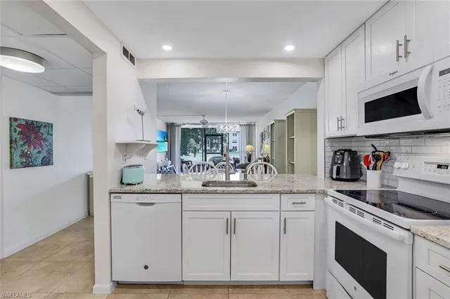 a kitchen with white cabinets and sink