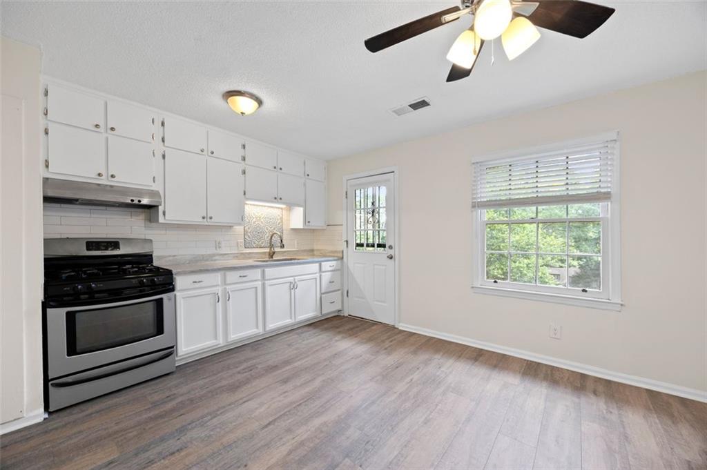 135 East Hill Street, Unit 22 Decatur, GA 30030 - Photo 12 of 18 a kitchen with stainless steel appliances granite countertop a stove a sink and white cabinets with wooden floor