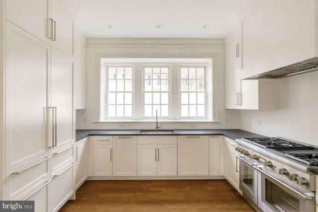 a view of an empty room with wooden floor fireplace and a window