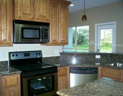 a kitchen with granite countertop a stove a sink and a microwave