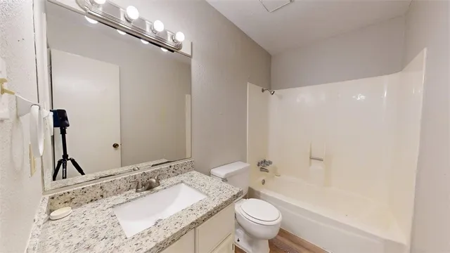 a bathroom with a granite countertop sink a toilet and a mirror