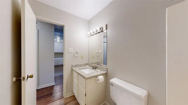 a bathroom with a granite countertop toilet a sink and a mirror
