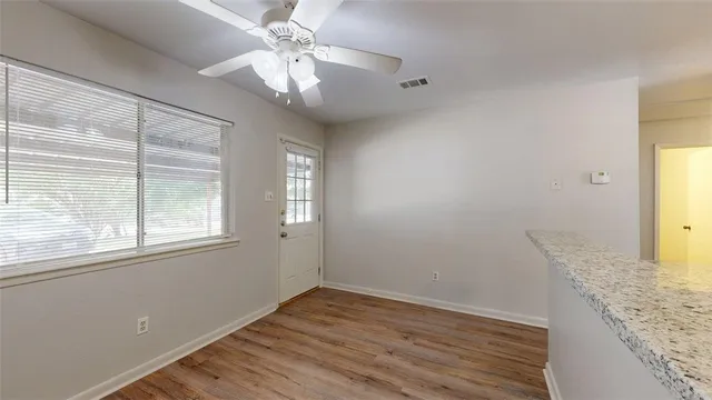 an empty room with wooden floor fan and windows