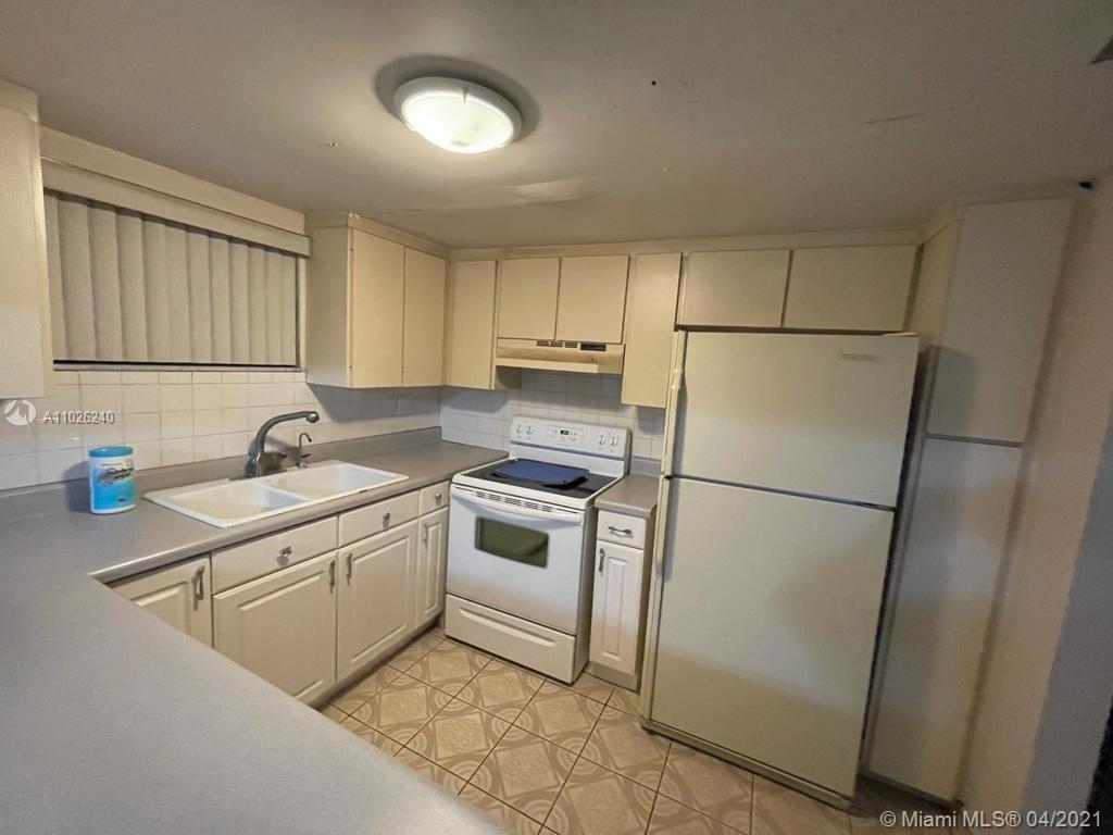 5900 West 18th Avenue, Unit A14 Hialeah, FL 33012 - Photo 11 of 29 a kitchen with a sink a refrigerator and cabinets