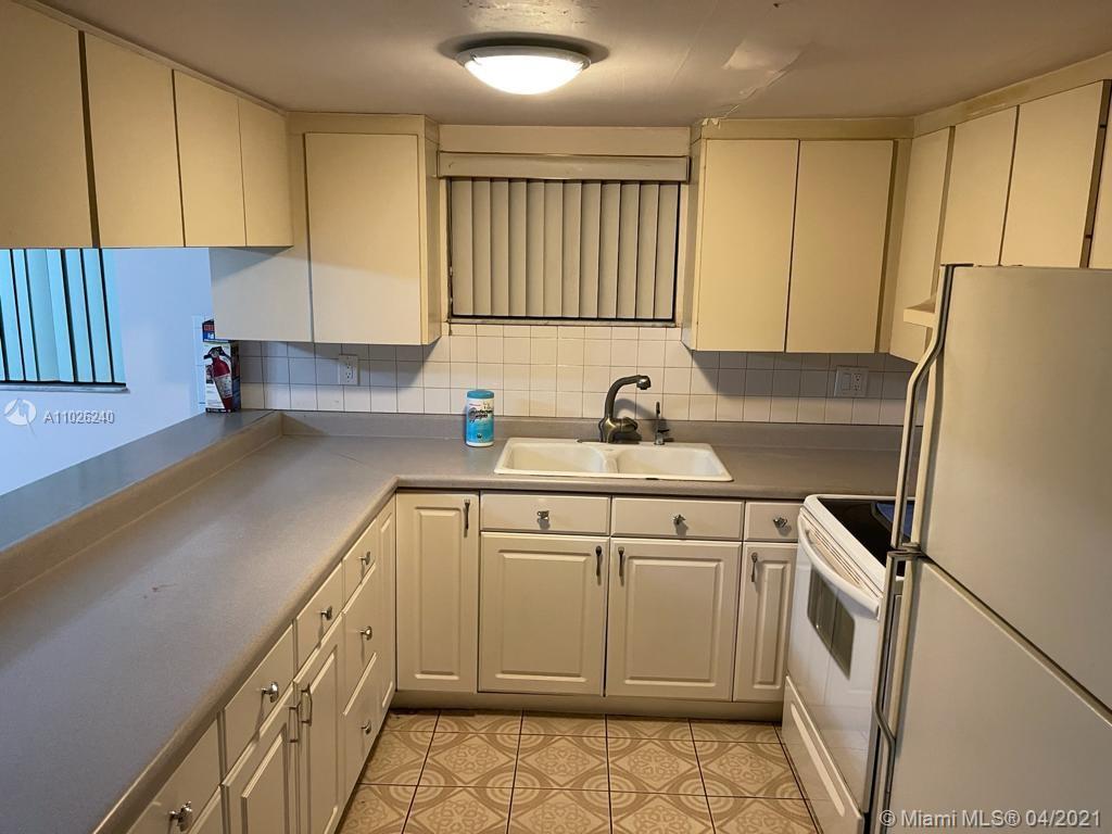 5900 West 18th Avenue, Unit A14 Hialeah, FL 33012 - Photo 9 of 29 a kitchen with a sink a refrigerator and cabinets