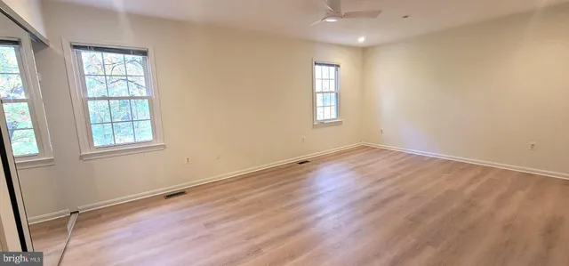 an empty room with wooden floor and windows