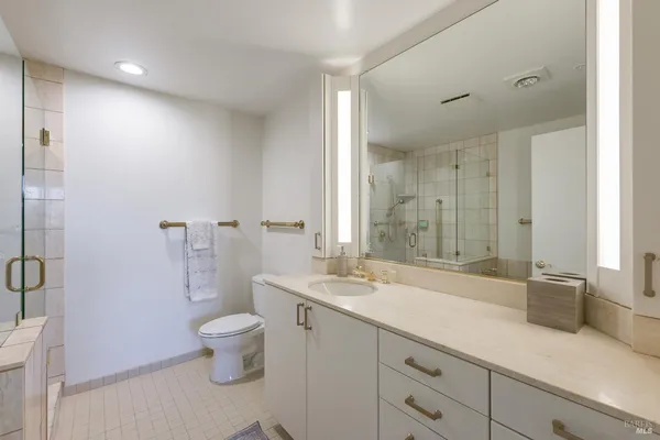 a spacious bathroom with a granite countertop sink a toilet and a large mirror