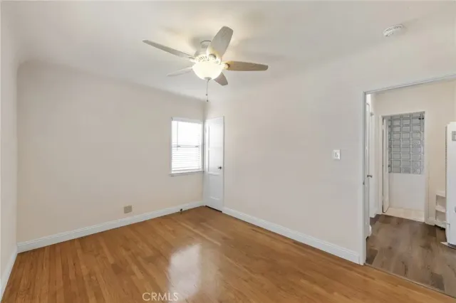 an empty room with wooden floor fan and windows