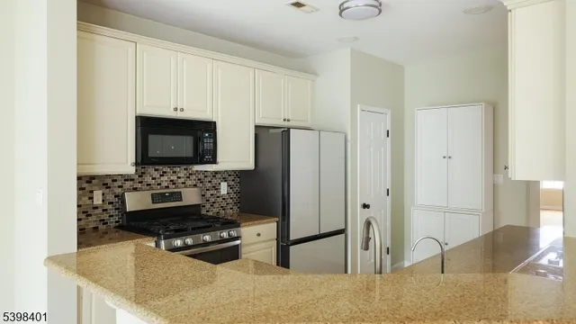 a kitchen with stainless steel appliances granite countertop a stove a refrigerator and a microwave
