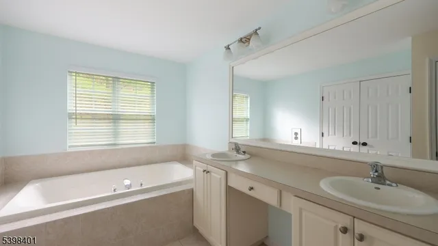 a bathroom with a tub a sink and mirror