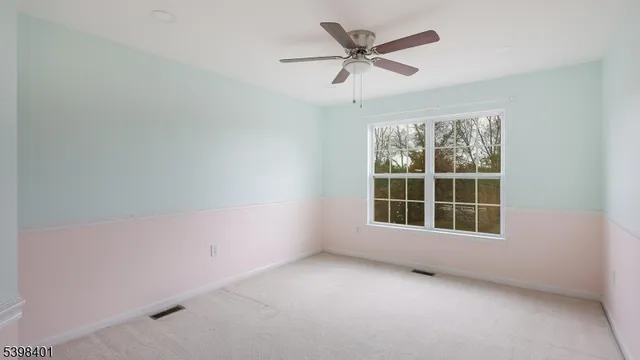 an empty room with a ceiling fan and windows