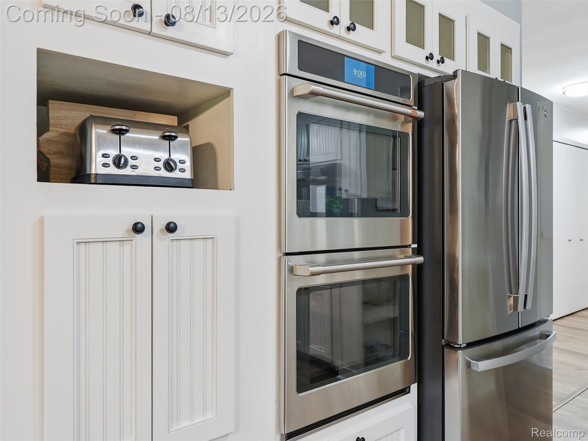 197 Perrydale Street Rochester, MI 48306 - Photo 14 of 50 Stainless steel double oven, stainless steel refrigerator, white cabinetry with beadboard detailing, and upper cabinets with frosted glass panels