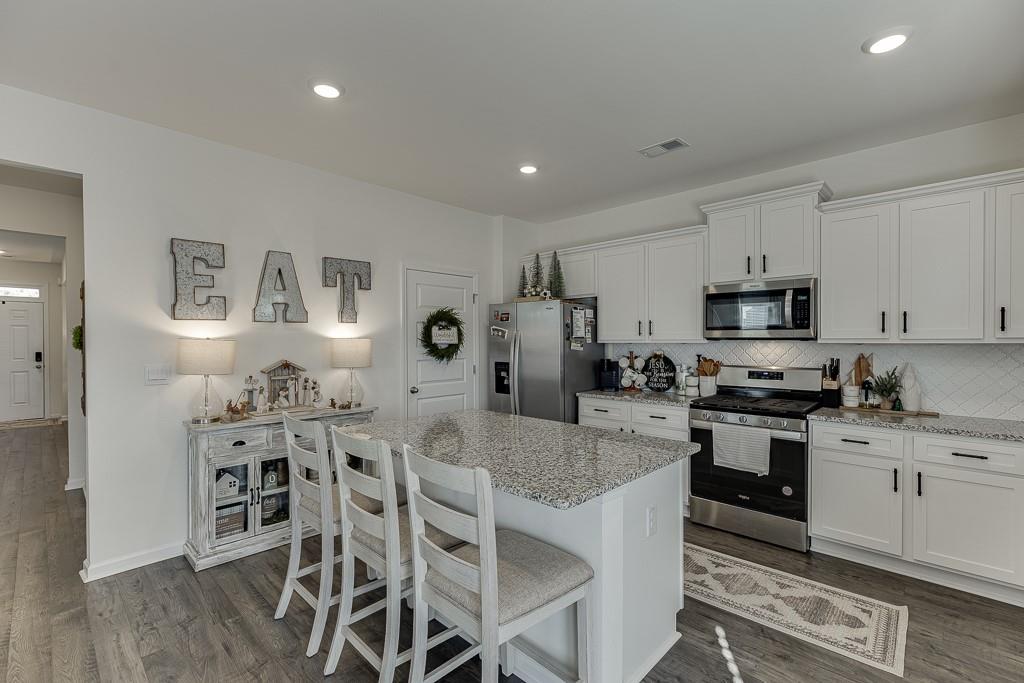 236 Ralph Still Road Dacula, GA 30019 - Photo 10 of 68 a kitchen with stainless steel appliances granite countertop a stove top oven a sink a refrigerator with white cabinets and wooden floor