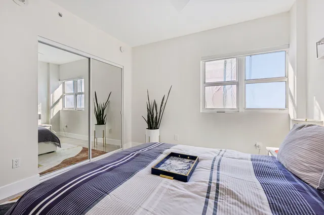 a bedroom with a large bed a potted plant and a window