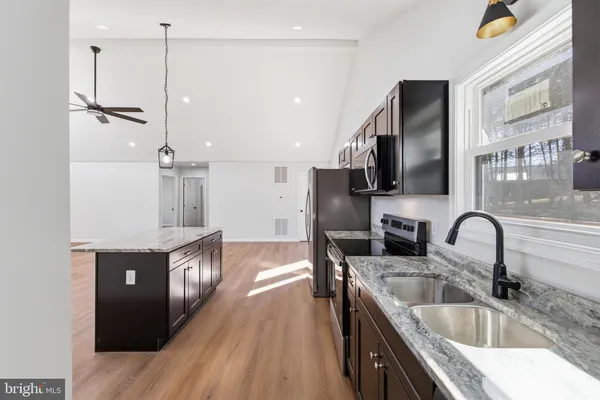 an empty room with wooden floor chandelier fan and windows