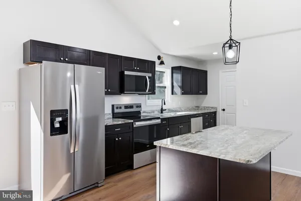 an empty room with wooden floor chandelier entryway and windows