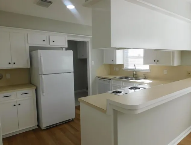 a kitchen with refrigerator a stove a sink and a granite counter tops with wooden floors