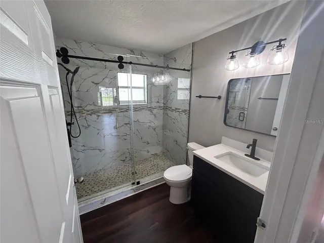 a bathroom with a shower sink vanity and toilet