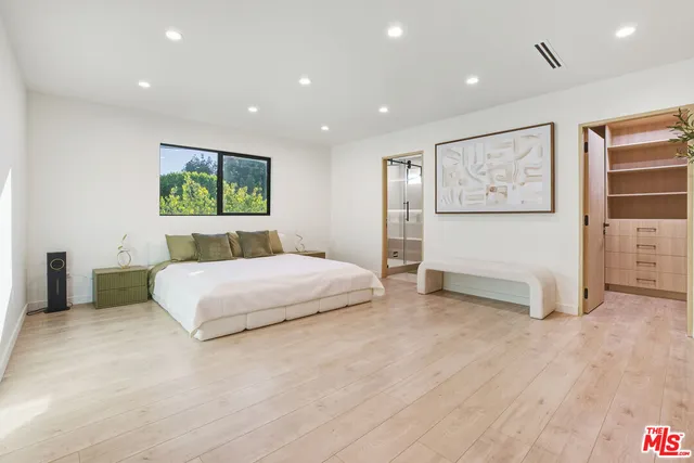 a spacious bedroom with a large bed and painting on the wall