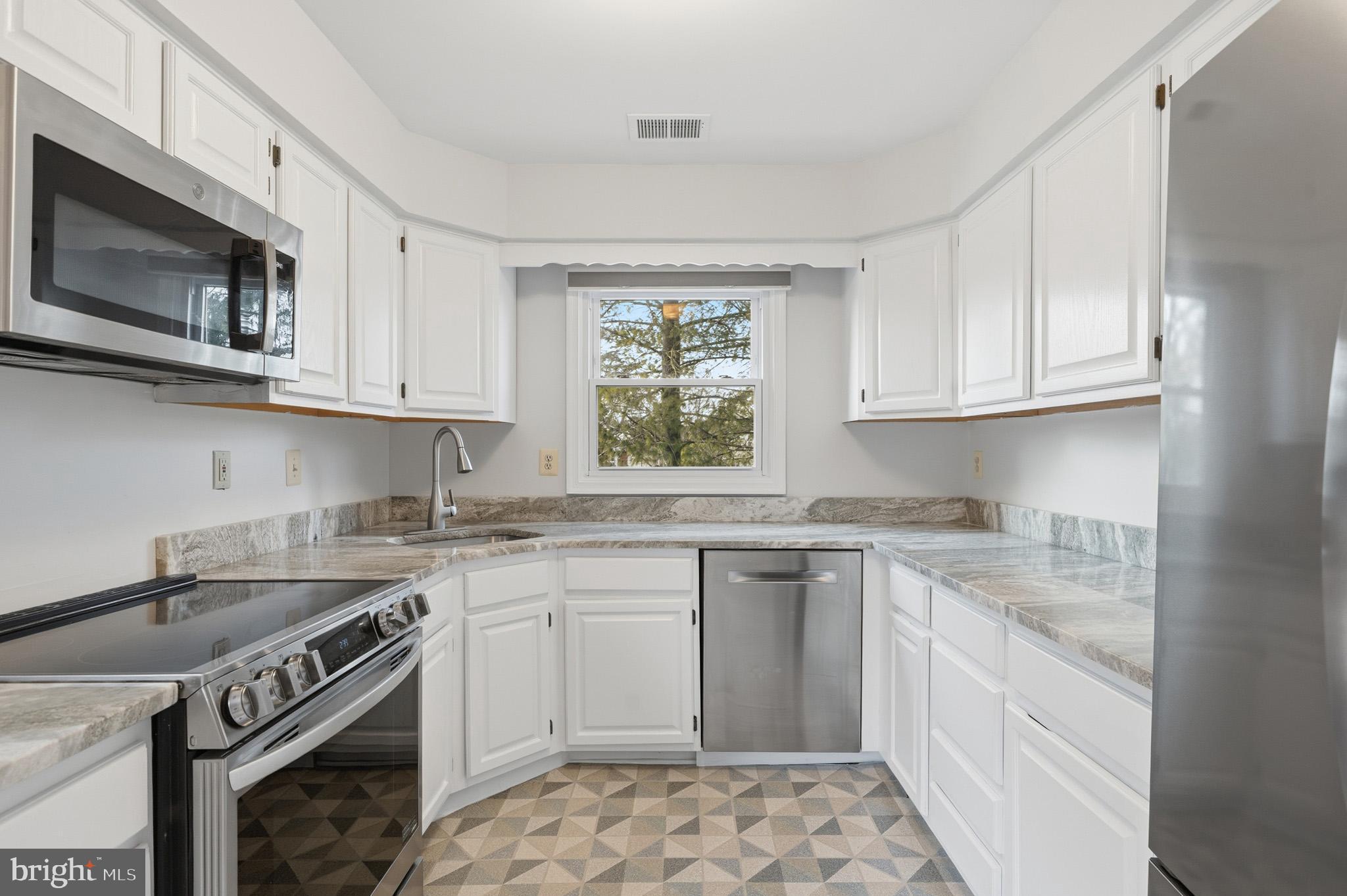 9146 Hardesty Drive Clinton, MD 20735 - Photo 27 of 47 a kitchen with stainless steel appliances granite countertop a sink stove a microwave and cabinets