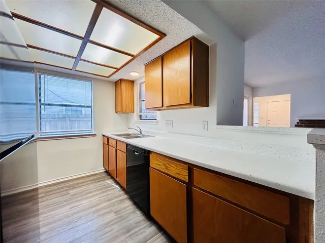 a kitchen with stainless steel appliances granite countertop wooden cabinets a sink and dishwasher with wooden floor