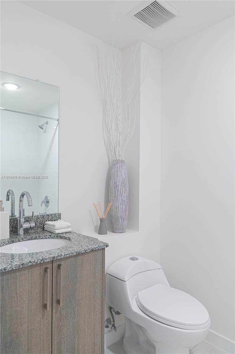 514 Southwest 22nd Avenue, Unit 204 Miami, FL 33135 - Photo 13 of 22 a bathroom with a granite countertop toilet sink and mirror