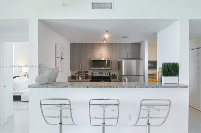 a kitchen with stainless steel appliances kitchen island granite countertop a stove a sink and a microwave