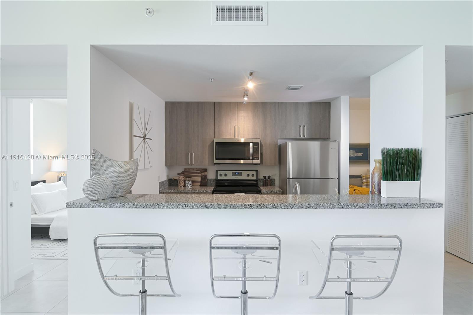 514 Southwest 22nd Avenue, Unit 204 Miami, FL 33135 - Photo 5 of 22 a kitchen with stainless steel appliances kitchen island granite countertop a stove a sink and a microwave