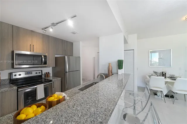 a kitchen with stainless steel appliances granite countertop a stove refrigerator and a sink
