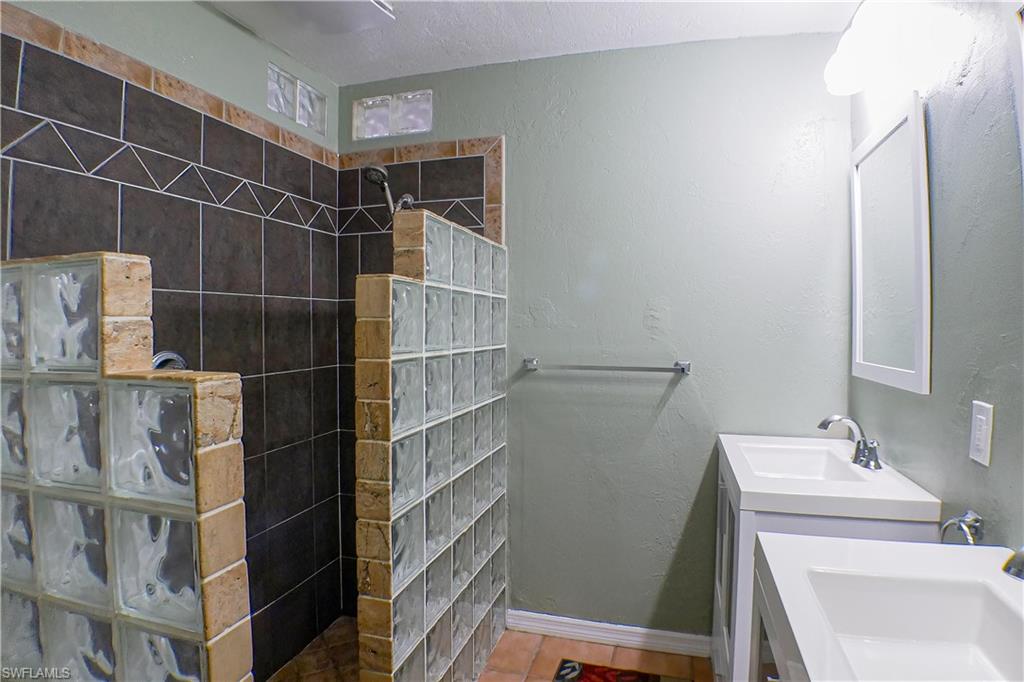 1056 Cardinal Street Naples, FL 34104 - Photo 23 of 32 Bathroom with a tile shower, tile flooring, double sink vanity