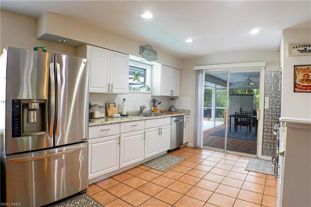 1056 Cardinal Street Naples, FL 34104 - Photo 7 of 32 Kitchen with stainless steel appliances, tasteful backsplash, white cabinetry, sink, and tile floors