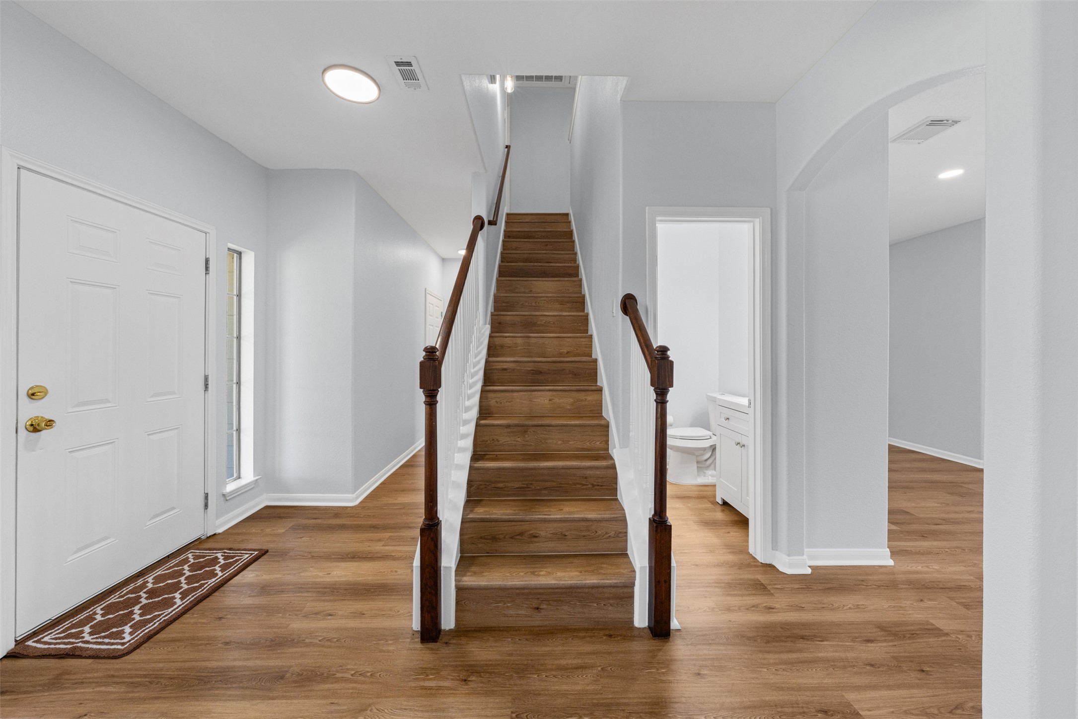 243 Engineers Pass Jarrell, TX 76537 - Photo 18 of 40 Entryway with wood-finish flooring, a white paneled front door with a sidelight, and a staircase featuring wood treads and a dark wood banister