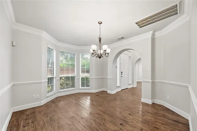 a view of a room with wooden floor chandelier and windows