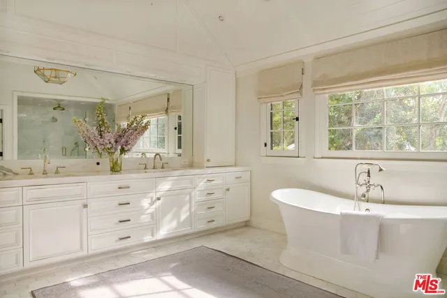 a bathroom with a tub a sink and mirror
