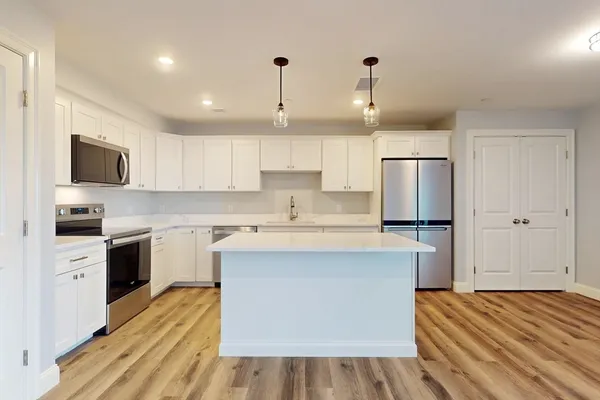 a kitchen with stainless steel appliances granite countertop a white stove top oven a sink dishwasher and a refrigerator with wooden floor