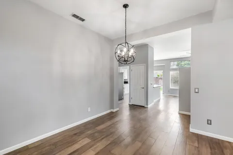 a view of a hallway with wooden floor and a chandelier