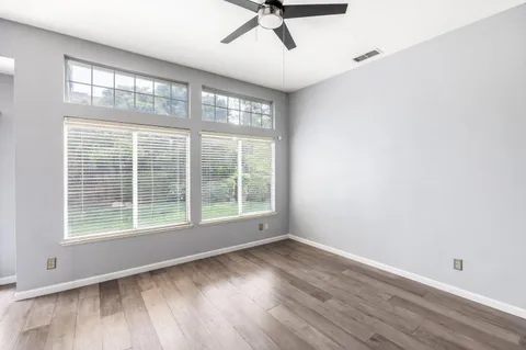 a view of empty room with wooden floor and fan