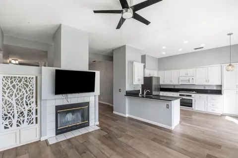 a kitchen with granite countertop a stove top oven a sink dishwasher and a fireplace with wooden floor