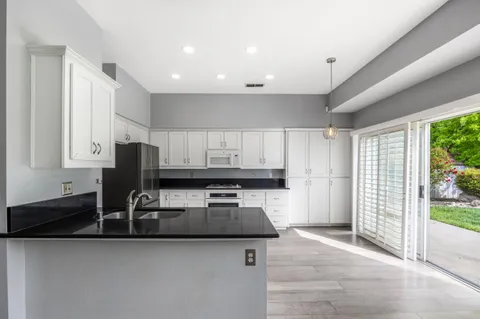 a kitchen with granite countertop a sink a counter top space and cabinets