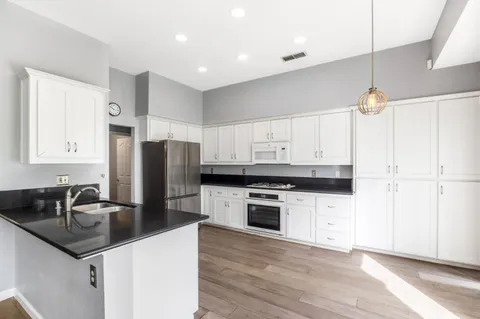 a kitchen with granite countertop a refrigerator stove and sink
