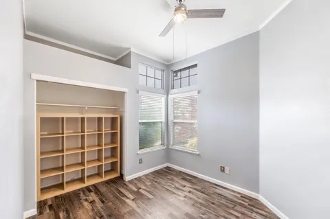 a view of an empty room with a window and wooden floor
