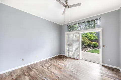 an empty room with wooden floor fan and windows