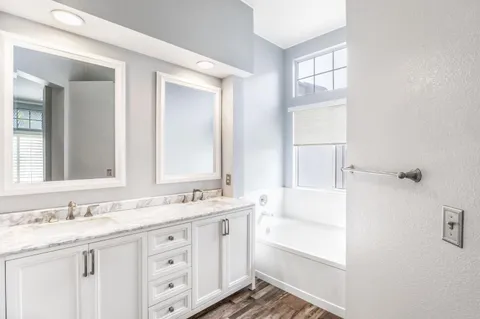 a bathroom with a granite countertop sink a mirror and a bathtub