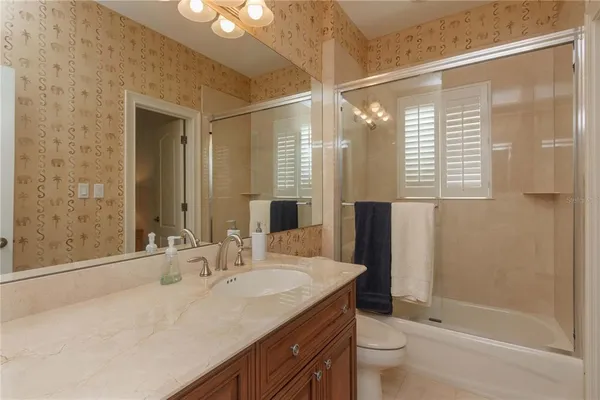 a bathroom with a granite countertop sink a toilet and shower
