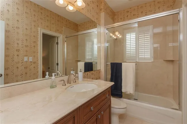 a bathroom with a granite countertop sink a toilet and shower