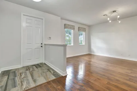 an empty room with wooden floor and windows