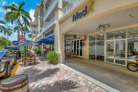 a front view of multi story residential apartment building with yard and sign board