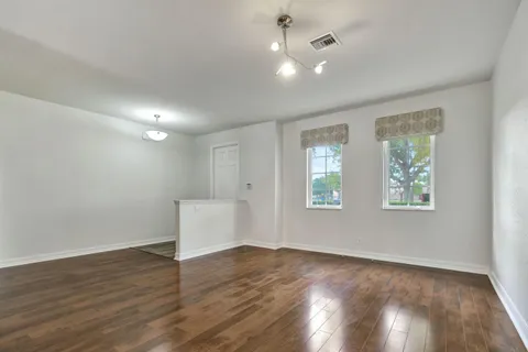an empty room with wooden floor and windows